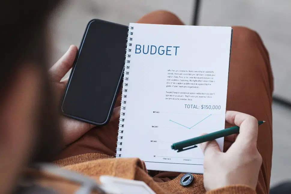 Man holding budget book and pen with phone, ready to compute his company budget