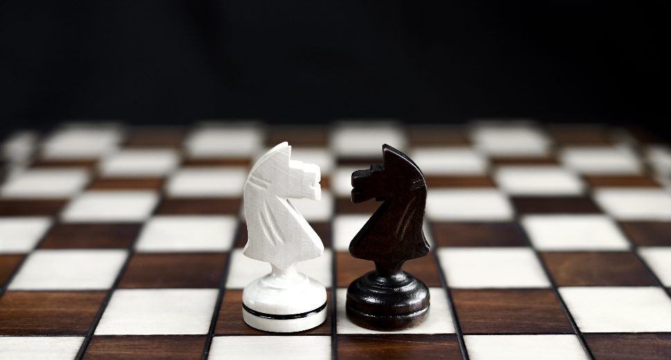 Two chess pieces facing off on a chess board